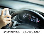Small photo of Hand of woman is spraying alcohol,disinfectant spray on steering wheel in her car,prevent infection of Covid-19 virus,contamination of germs or bacteria,wipe clean surfaces that are frequently touched