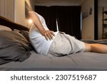 Small photo of Stressed asian man having a backache,sore hips,waist hurts,unhappy adult people suffering from low lumbar pain or acute back strain,lying on the mattress at home,health care,medical,lifestyle concept