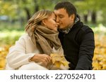 Small photo of Young man and woman gently embrace in the autumn park. Beautiful couple with golden autumn leaves. Love and fidelity. Close-up.