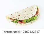 Small photo of Italian street food flat lay with piadina isolated on a white background. Piadina romagnola - Italian flatbread with prosciutto, salad and cream cheese