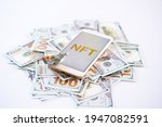 Non-fungible token NFT, crypto art, digital art, new type of cryptorurrency. Cell phone with golden NFT text in golden frame as art object on dollars background