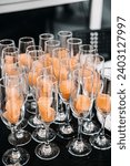 Small photo of Elegant Champagne Glasses with Sorbet for Catering Event. Rows of champagne glasses filled with refreshing orange sorbet, prepared for a sophisticated catering event or celebration.
