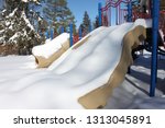 Small photo of When the Polar Vortex came through, it left everything covered in deep snow. It'd be tough to slide down these slides. Snowy playground on a background of conifers, taken in Pretence Park, Ashland, WI