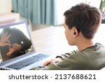 Small photo of Deaf teenager boy Wearing Hearing Aid using Laptop. Disable student with disabilities deafness distancing learning online from home making communication hands language with teacher via VDO call.