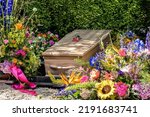 Small photo of People loss and mourning concept, a wooden coffin with beautiful flowers arrangement before funeral or burial at cemetery, a funeral service.