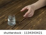 Small photo of A woman's hand reaches for a wine-glass with alcohol, a wooden background, a close-up, a ghastly alcoholism