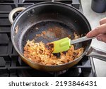 Small photo of A spatula for stirring food picks off burnt food in a pan. Poor quality Teflon coated pans.