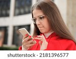 Small photo of portrait of young myopic purblind student teen teenager girl looking at screen of her smartphone, using cell mobile phone in glasses. Vision eyes problems, myopia, blindness.