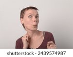 Small photo of Amused woman with puckered lips, wide eyes, and playful pose