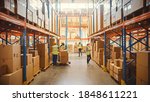 Small photo of Retail Warehouse full of Shelves with Goods in Cardboard Boxes, Workers Scan and Sort Packages, Move Inventory with Pallet Trucks and Forklifts. Product Distribution Delivery Center.