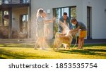 Small photo of Smiling Father, Daughter, Son Play With Loyal Golden Retriever Dog, Spraying Each other with Garden Water Hose. On a Sunny Day Family Having Fun Time Together Outdoors in Backyard.