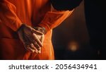 Arrested Handcuffed Convict at a Law and Justice Court Trial. Handcuffs on Accused Criminal in Orange Jail Jumpsuit. Law Offender Sentenced to Serve Jail Time.