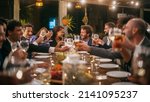 Small photo of Big Dinner Party with a Small Crowd of Multiethnic Diverse Friends Celebrating at a Restaurant. Beautiful Happy Hosts Propose a Toast and Raise Wine Glasses while Sitting at a Table in the Evening.