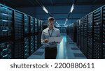 Small photo of Futuristic Concept: Big Data Center Chief Technology Officer Using Laptop Standing In Warehouse, Information Digitalization Lines Streaming Through Servers. SAAS, Cloud Computing, Web Service