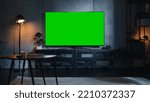 Small photo of Stylish Loft Apartment Interior with TV Set with Green Screen Mock Up Display Standing on Television Stand. Empty Cozy Living Room of Spacious Flat with Chroma Key Placeholder on Monitor.