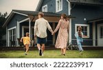 Small photo of Young Beautiful Couple Walking Outdoors Towards the Country House, Holding Hands. Their Little Son and Daughter Running Together with Them. Young Modern Family at Home, Footage from The Back.