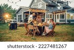 Small photo of Big Family Garden Barbecue Party Celebration, Gathered Together at a Table with Relatives and Friends. Young and Senior People are Eating, Drinking, Passing Dishes, Joking and Having Fun.