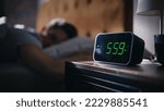 Small photo of Handsome Man Wakes Up and Turns off Alarm Clock. Proceeds to Have a Productive Day of Work. Stylish Apartment. Focus on the Clock Showing Five Hours and Fifty Nine Minutes in the Morning