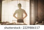 Small photo of Caucasian Young Man Waking up in the Morning, Stretches and Gets Out of Bed, Sun Shines From the Window, He is Ready for Business Opportunities, Achievements, Adventures. Seize the day