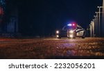 Small photo of Low Angle Shot of a Stopped Police Car with Lights and Siren on During a Misty Night. Patrolling Vehicle on Stand by, Waiting for Orders to Start Pursuing Suspects. Police Enforcement
