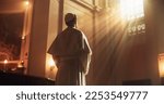 Small photo of Christian Bishop Standing in Front of a Window In Church, Reflecting on Earthly Life and Mortality. He is Illuminated by the Light of Faith and Trust in the Guidance From Jesus Christ and the Bible