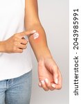 Small photo of Allergic reaction, itch, allergy, dermatiti concept. Close up of woman applying cream or ointment on swell reddened skin after insect mosquito bites, isolated on grey studio background.