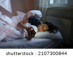 Small photo of Social media jealousy. Young depressed woman addicted to mobile phone lying in bed at home, scrolling social media, feeling envious of lives of others, reading what people posting and sharing online