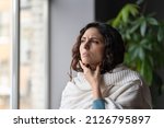Small photo of Upset sick woman touching painful swollen neck glands, suffering from throat infection, unhealthy female standing near window at home feeling pain with swallowing, selective focus