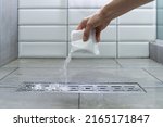Small photo of Closeup of woman hand pouring pipe cleaner granules. Removal of blockage in the shower of a special remedy with powder. Clean the blockages in the bathroom with chemicals.