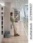 Small photo of Full length of pensive middle-aged woman book nerd reads interesting paper covered book in library, focused pensive female devoted to reading and study, mature student with textbook near bookcase
