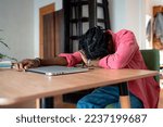 Exhausted overloaded African guy remote worker sleeping on desk while working remotely from home, suffering from freelancer burnout. Student guy experiencing sleep deprivation from virtual learning
