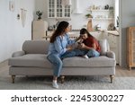 Small photo of Loving mother sitting with sad daughter on sofa at home, helping child to cope with friendship breakup. Disappointed teen girl looking at phone screen, sharing feelings with mom. First love concept