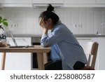 Small photo of Tired exhausted woman sit at kitchen table with laptop leaning head on hands and feels burnt out after inconclusive work. Young casual girl student doing distance education getting knowledge from home