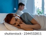 Small photo of Upset wife lies with her back to husband. Frustration, unhappiness, pain, resentment and thoughtfulness on face of sad depressed woman lying in bed thinking. Man with disinterested look ignores woman.