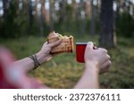 Small photo of Man eating sandwich drinking tea having halt in forest enjoying nature, hands close-up. Guy hiker having break resting in woodland, mountains. Outdoors activity, camping, hiking, trekking concept.