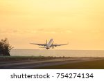 Airplane taking off during a beautiful sunset above the sea. Silhouette of plane fly up at wonderful sunset yellow sky background. Ban on air travel during the coronavirus pandemic