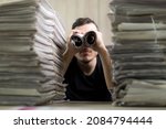 Man holding two twisted roll newspaper. Metaphor or allegory with binoculars. Selective focus on newspapers. Truth search concept