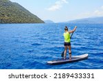 Young woman paddleboarding on a SUP board in the Mediterranean Sea. Supsurfing is a popular outdoor activity. Stand up paddle boarding