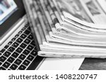 Small photo of Newspapers and laptop. Pile of daily papers with news on the computer. Pages with headlines, articles folded and stacked on keypad of electronic device. Modern gadget and old journals, focus on paper