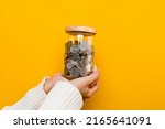 Small photo of Hands and coins in a savings jar money saving on yellow background money saving concept Plant a plan to save money for children.
