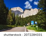 Scenic road to the Sella Pass in Dolomites, South Tyrol (Sudtirol, Alto Adige), Italy, with high rock wall of Sella group seen in background