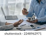 Small photo of House purchase concept, real estate agent with house model talking to client about buying home insurance and client signing contract under formal contract agreement with real estate law