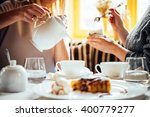 Cafe or bar table with desserts and tea. Two people talking on background.