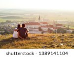Young tourist couple overlooking romantic Mikulov Castle, South Moravia Region, Czech Republic. Sunset landscape panoramic view of landmark and town in summer. Popular tourist attraction.
