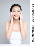 Small photo of Portrait of cheerful laughing Asian woman applying foam for washing on her face with attractive appearance. Skincare spa relax concept. Isolated on grey background