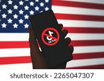 Small photo of TikTok app logo crossed out with red Ban sign displayed on phone screen with the US flag background. TikTok getting banned in the USA concept. Swansea, UK - February 21, 2023.