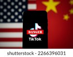 Small photo of TikTok app logo crossed out with red Danger sign displayed on phone screen with the US and China flags background. Tik Tok ban in the USA concept. Swansea, UK - February 23, 2023.