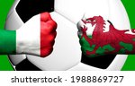 Flags of Italy and Wales painted on two clenched fists facing each other with closeup 3d football soccer ball in the background. Mixed media football match game concept