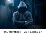 Small photo of dangerous criminal. scary hooded man at night in dark alley. silhouette bandit, criminal with an unrecognizable face in threatening pose at night on dark street. Mysterious man in silhouette