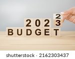Business concept of planning 2023. Businessman flips wooden cube and changes words BUDGET 2022 to BUDGET 2023. New year business plan concept in 2023. Economy and business.Phrase 2023 BUDGET